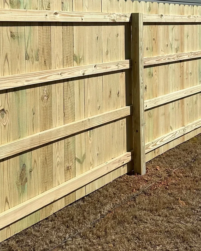 A wide wooden double drive gate hung on heavy posts